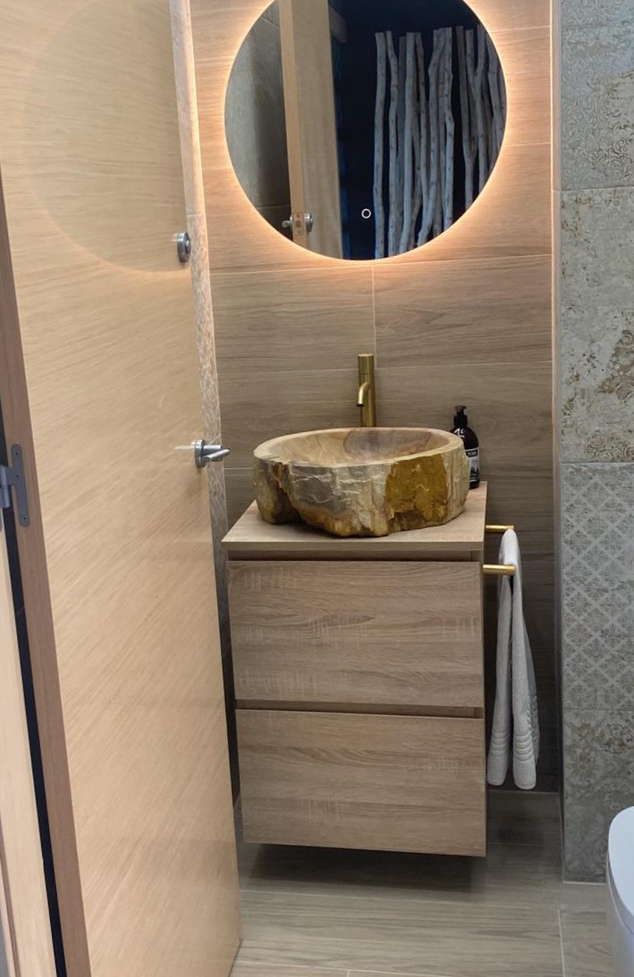 Detalle de baño con materiales naturales y lavabo sobre encimera