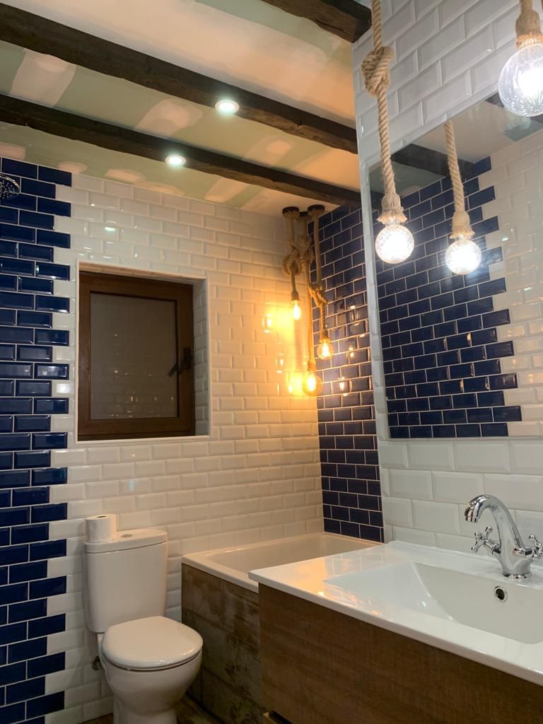 Baño reformado con azulejo blanco y azul e iluminación suspendida