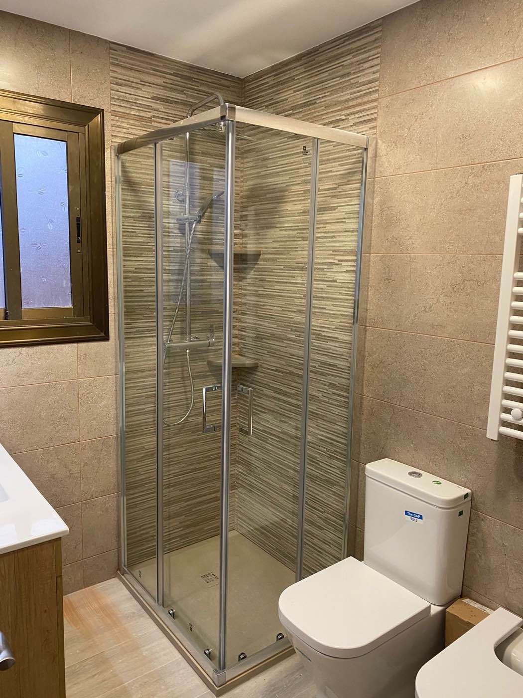 Baño terminado con ducha, mampara y revestimiento cerámico