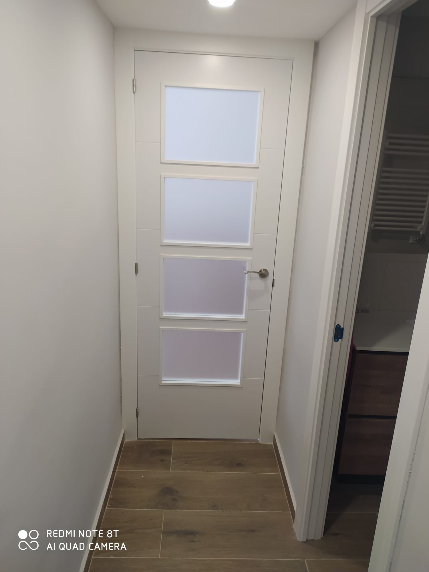 Puerta interior blanca con paneles de vidrio instalada