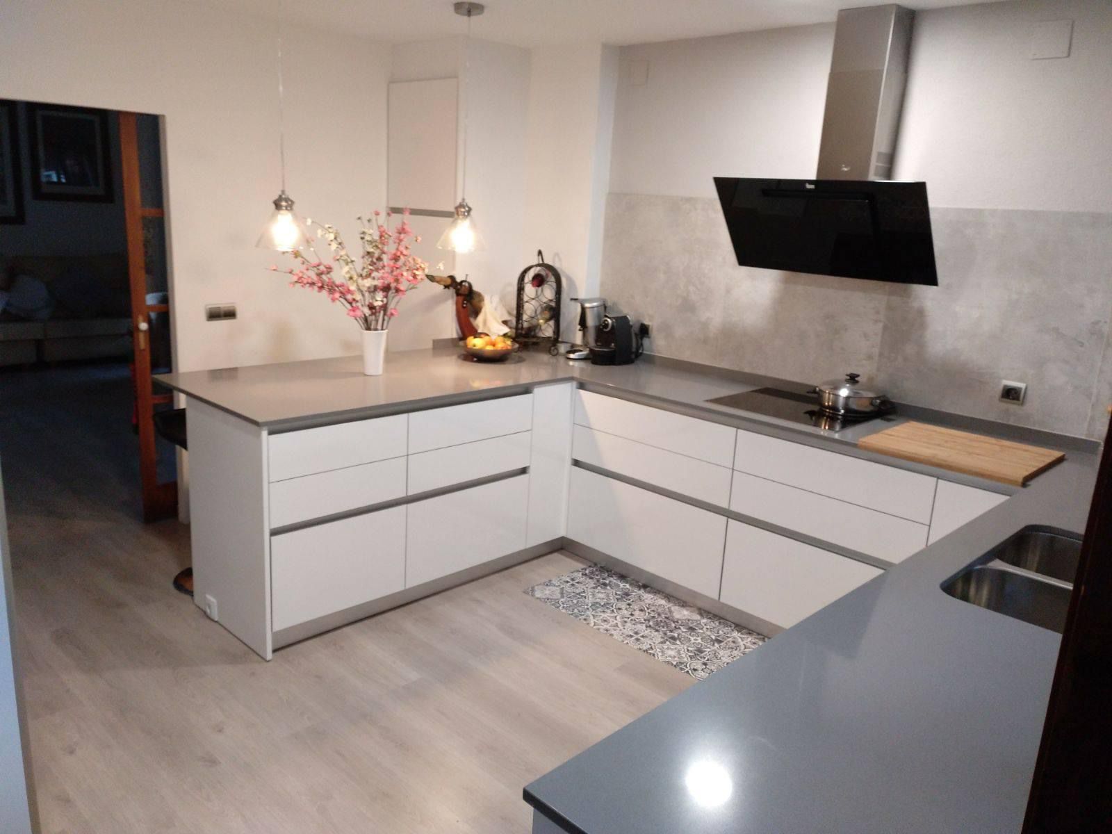 Cocina terminada con encimera gris y mobiliario blanco